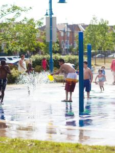 Children play in an urban splash park as adults look on