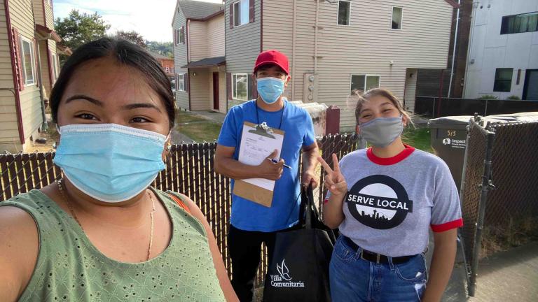 Three socially distanced volunteers pose with masks on