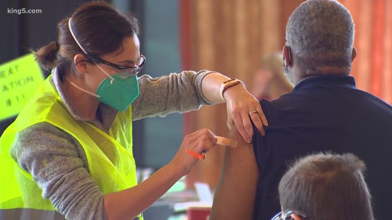 A health care worker administers a bandaid to a patient's upper arm