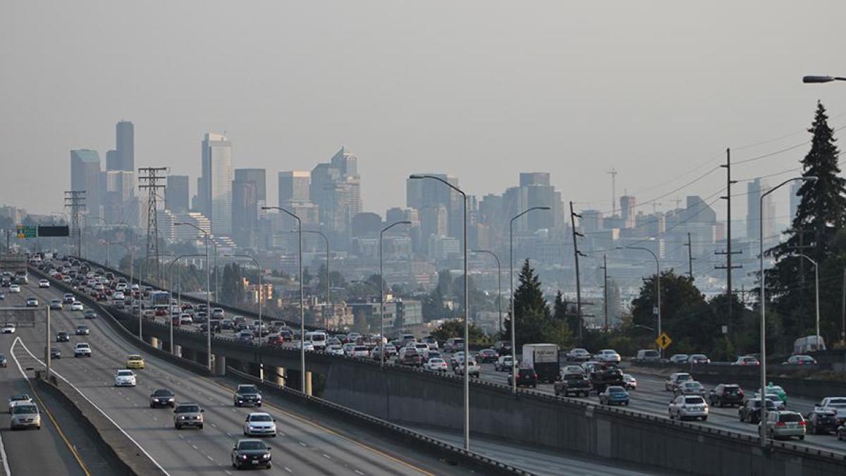 Photo of downtown seattle and interstate 5 with heavy traffic. A haze of pollution obscures the buildings of downtown.