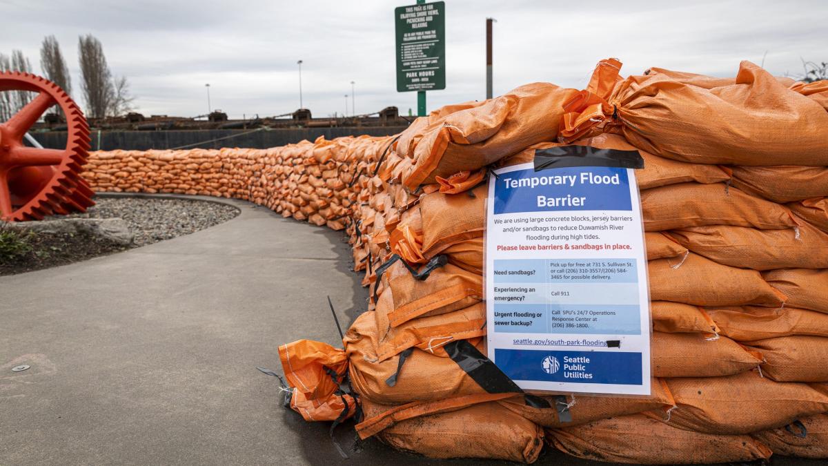 Image of orange sand bags with sign reading "Temporary Flood Barrier"