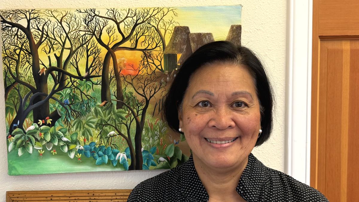 Maria Batayola stands in front of a colorful painting.