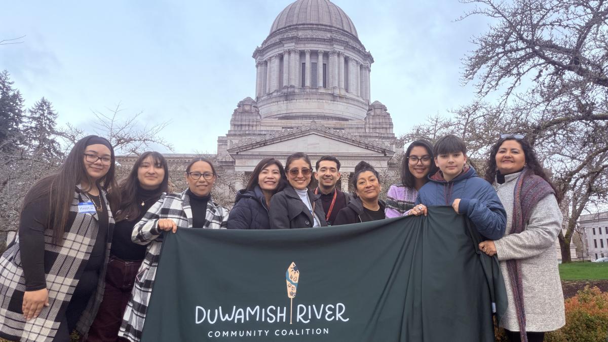 A group of people hold a banner with the logo of the Duwamish River Community Coalition in front of the Washington State capitol building
