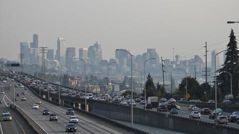 Photo of downtown seattle and interstate 5 with heavy traffic. A haze of pollution obscures the buildings of downtown.