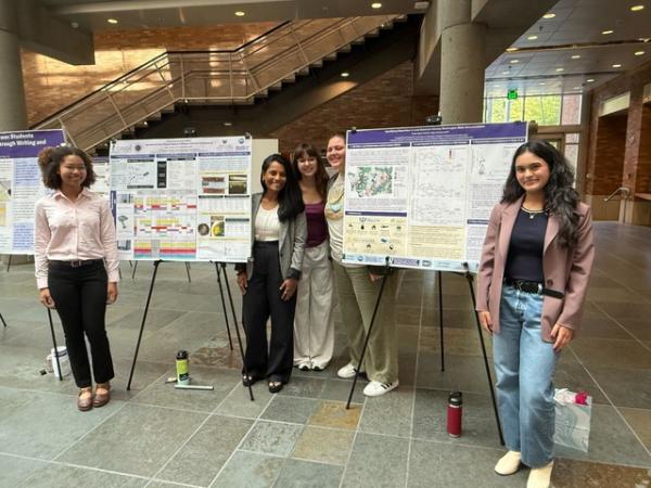 Five researchers pose with research posters