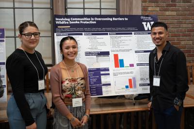 Three students pose by a research poster.